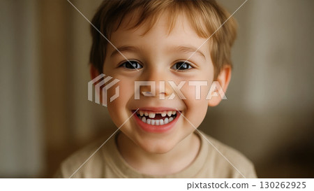 Smiling young boy with missing baby tooth showing happy face and natural expression in warm indoor light 130262925
