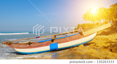 Tropical Beach with a Traditional Fishing Boat at Sunrise 130263333