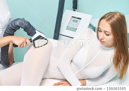 Young caucasian female receiving non-invasive body sculpting treatment at spa 130263385