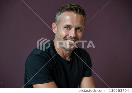 Confident Man Smiles Against Purple Background in Black Tee Confident Man Smiles Against Purple Background in Black Tee 130263704