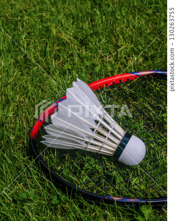 Close-up of a badminton shuttlecock placed on a racket, lying on fresh green grass, perfect for representing outdoor games and sports activities. High quality photo Close-up of a badminton shuttlecock placed on a racket, lying on fresh green grass, perfect for representing outdoor games and sports activities. High quality photo 130263755