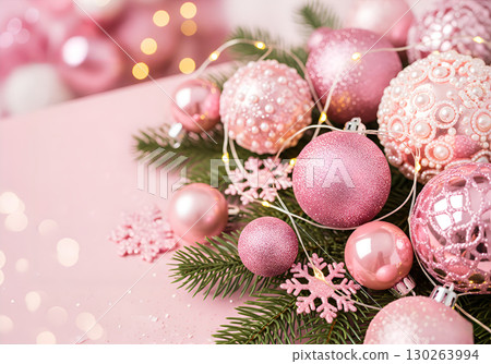 Christmas toys on a snow-covered spruce branch in rose and gold tones. 130263994