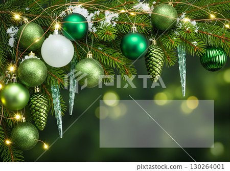 Winter composition with green Christmas balls, garland and icicles on a snow-covered branch. 130264001
