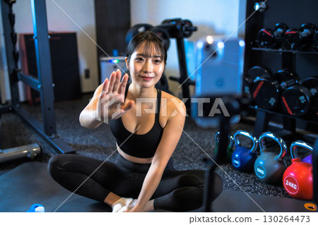 一位20多歲的女性在視訊直播中向粉絲揮手致意。一位酷炫的女子正在健身房鍛鍊。一位主播。 一位20多歲的女性在視訊直播中向粉絲揮手致意。一位酷炫的女子正在健身房鍛鍊。一位主播。 130264473