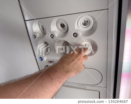 Male hand adjusting air vent in airplane cabin. Passenger comfort, aviation technology, and travel experience. Male hand adjusting air vent in airplane cabin. Passenger comfort, aviation technology, and travel experience. 130264687