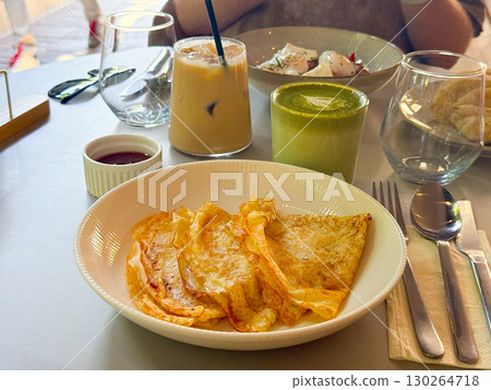 Thin pancakes served with sauce. Breakfast with iced coffee and matcha latte. 130264718