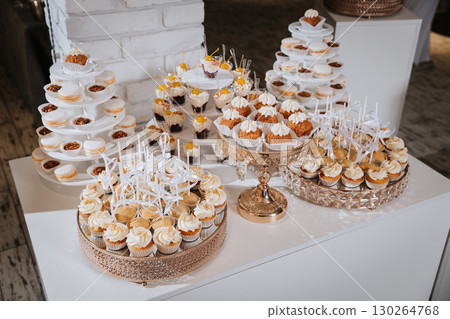 Luxury dessert table with cupcakes, macarons, and mini sweets at elegant event Luxury dessert table with cupcakes, macarons, and mini sweets at elegant event 130264768