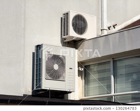 Air conditioning units attached to exterior building wall near window and balcony. Urban architecture, ventilation technology, and modern household infrastructure 130264783