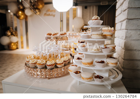Elegant dessert table with white mousse cubes on cookies in luxury golden trays Elegant dessert table with white mousse cubes on cookies in luxury golden trays 130264784