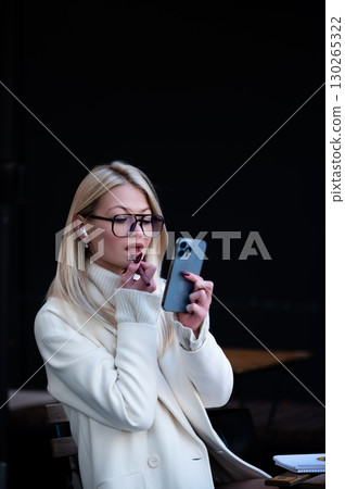 Engaging in a moment of thought and connection while checking a smartphone in a cozy urban cafe during the late afternoon 130265322