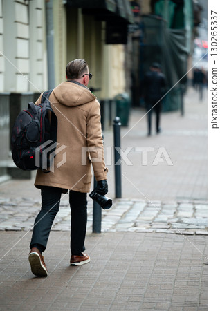 Photographer exploring a vibrant city street while capturing moments on a chilly day, blending urban energy with creative artistry Photographer exploring a vibrant city street while capturing moments on a chilly day, blending urban energy with creative artistry 130265337