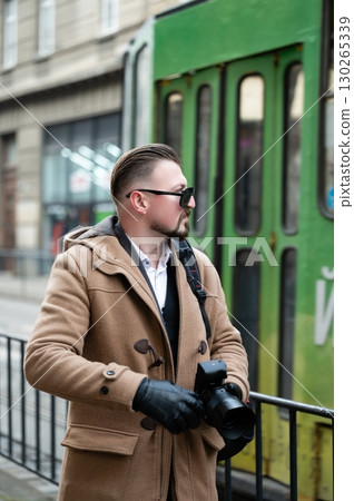 Stylish photographer capturing urban moments while standing beside a green tram in a bustling city during the early afternoon Stylish photographer capturing urban moments while standing beside a green tram in a bustling city during the early afternoon 130265339