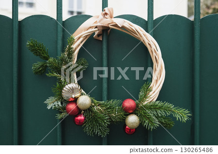 Christmas wreath with branches and red balls on a green door Christmas wreath with branches and red balls on a green door 130265486