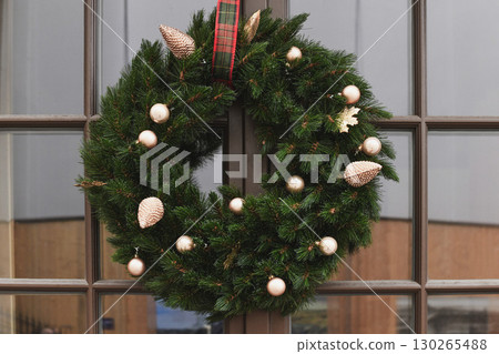 Christmas wreath with branches and golden balls on a glass door 130265488