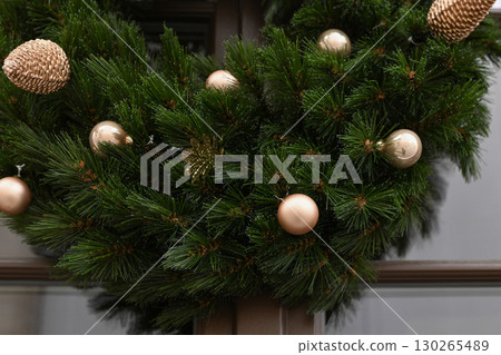 Christmas wreath with branches and golden balls on a glass door Christmas wreath with branches and golden balls on a glass door 130265489