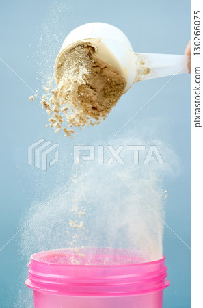protein powder spills in cup from measure scoop.  whey sports nutrition. dry mixture 130266075