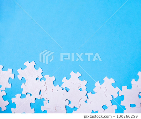 Blue background with a pile of white jigsaw puzzle pieces 130266259