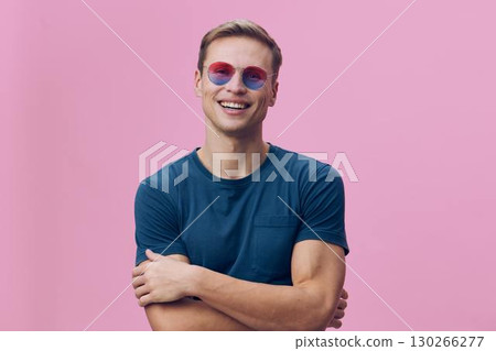 Smiling man wearing sunglasses and a casual teal t-shirt, smiling happily against a pink background, cheerful atmosphere, lifestyle concept. Smiling man wearing sunglasses and a casual teal t-shirt, smiling happily against a pink background, cheerful atmosphere, lifestyle concept. 130266277