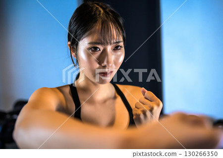 一個很酷的女人在健身房做拳擊練習，用右拳出拳 130266350