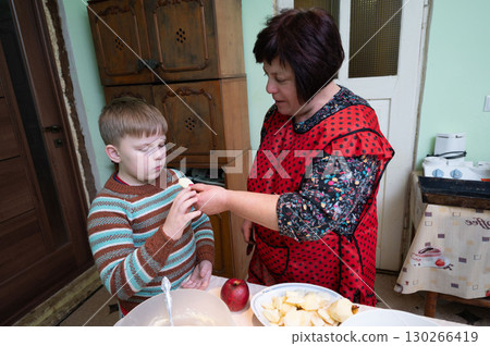 Mother and son share a cherished moment in the kitchen preparing a delicious apple dessert together on a cozy afternoon 130266419