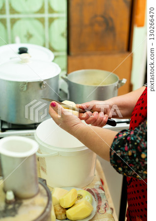 Hands skillfully peeling potatoes in a cozy kitchen, readying for a warm family meal in the heart of an inviting home environment filled with love and tradition Hands skillfully peeling potatoes in a cozy kitchen, readying for a warm family meal in the heart of an inviting home environment filled with love and tradition 130266470