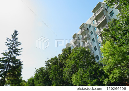 Modern apartment building with green trees and walkway 130266606