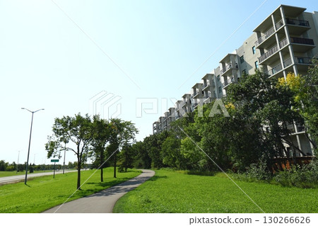 Modern apartment building with green trees and walkway 130266626
