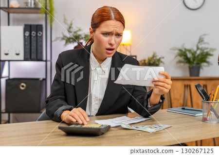 Young businesswoman checks bills with calculator sees negative balance worries about future expenses Young businesswoman checks bills with calculator sees negative balance worries about future expenses 130267125
