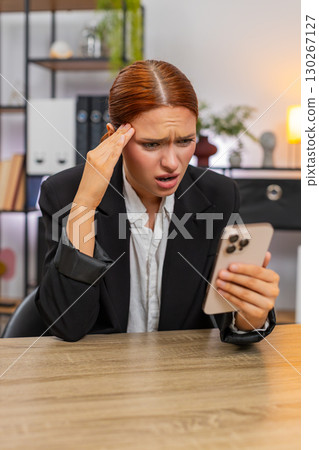 Young businesswoman despairs over big failure online game loss reading bad news sadly on smartphone Young businesswoman despairs over big failure online game loss reading bad news sadly on smartphone 130267127