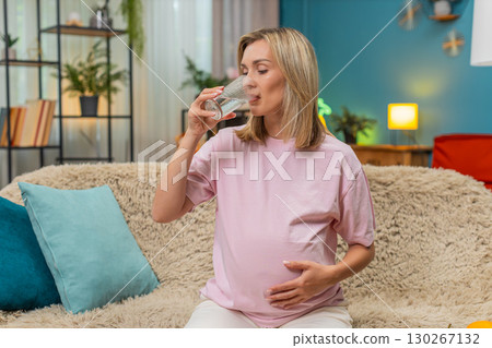Pregnant woman drinking pure water hand on belly showing hydration importance for healthy pregnancy Pregnant woman drinking pure water hand on belly showing hydration importance for healthy pregnancy 130267132