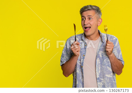 Man holding knife and fork looking at camera with hungry expression waiting for tasty delicious food 130267173
