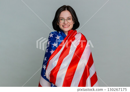 Young woman joyfully waving American USA flag with smile expressing patriotism support pride emotion 130267175