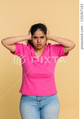 Indian woman abruptly covers ears with hands, expressing discomfort from loud annoying sound noise 130267183