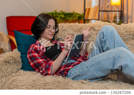 Young woman sketching in notebook at home, focused and inspired by creative process with calm energy Young woman sketching in notebook at home, focused and inspired by creative process with calm energy 130267200