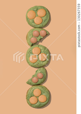 Pistachio cookies with creamy filling arranged vertically on a peach background, showcasing vibrant colors and textures, ideal for bakery concept and menu design with copy space 130267359