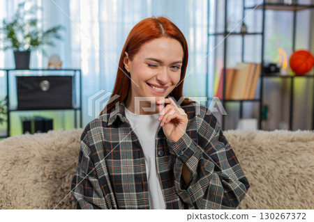 Young woman on sofa winking at camera with flirty smile showing playful mood and confident charm Young woman on sofa winking at camera with flirty smile showing playful mood and confident charm 130267372