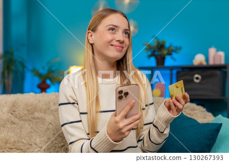 Caucasian woman paying purchase on sofa with mobile phone credit card smiling successful indoors 130267393