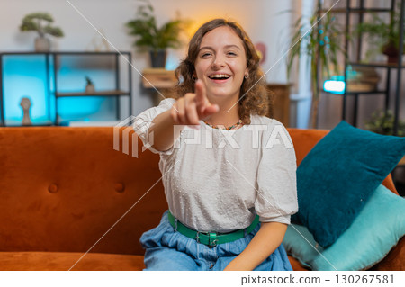 Young woman laughing out loud after hearing ridiculous funny joke sitting on sofa couch at home 130267581