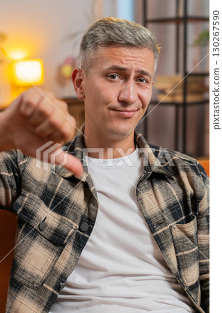 Upset unhappy man showing thumbs down dislike gesture expressing discontent disapproval dissatisfied 130267590