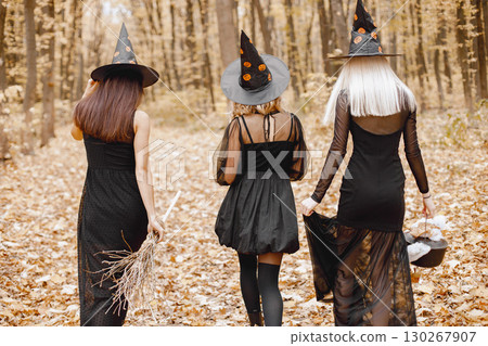 Three girls witches in forest on Halloween. Girls wearing black dresses and cone hats. Witches dance to make a magic potion. 130267907