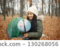 One little black girl in tent camping in the forest. Girl is holding a globe in her hands. Black girl wearing khaki coat and beige hat. 130268056