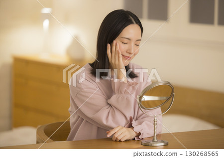 A woman doing skin care at night in her bedroom 130268565