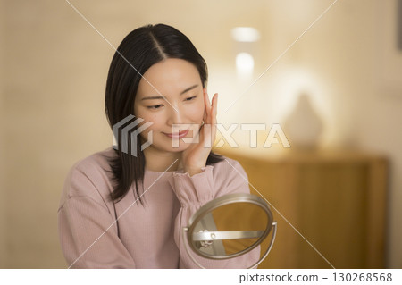 A woman doing skin care at night in her bedroom A woman doing skin care at night in her bedroom 130268568