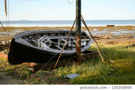 Abandoned wooden boat on empty beach with clear sky by White Sea in summer in Karelia, concept of travel in Russia 130268666