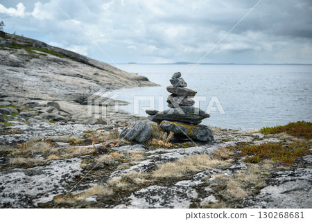 Balanced rock cairn on rugged coastal landscape under cloudy sky in White Sea, nature of Karelia. Balanced rock cairn on rugged coastal landscape under cloudy sky in White Sea, nature of Karelia. 130268681