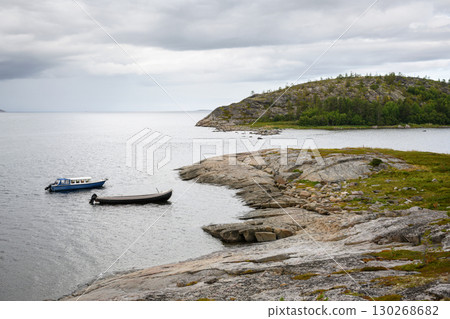 Serene coastal landscape with boats, water and rocky islands under cloudy sky in White Sea, nature of Karelia for travel theme Serene coastal landscape with boats, water and rocky islands under cloudy sky in White Sea, nature of Karelia for travel theme 130268682