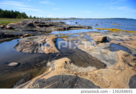 Scenic rocky shore with water and stones on a sunny day in White Sea, Russian Karelia, concept of northern landscape and nature Scenic rocky shore with water and stones on a sunny day in White Sea, Russian Karelia, concept of northern landscape and nature 130268691