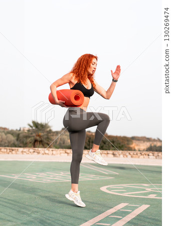 Fit woman in activewear exercising outdoors while Fit woman in activewear exercising outdoors while 130269474