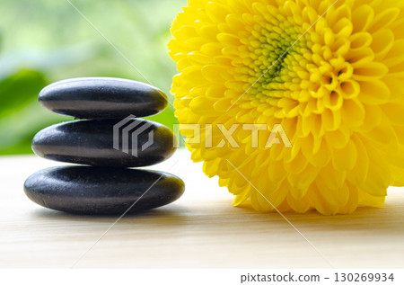 Yellow flower with black polished stones creating warm harmony with customizable space for text 130269934