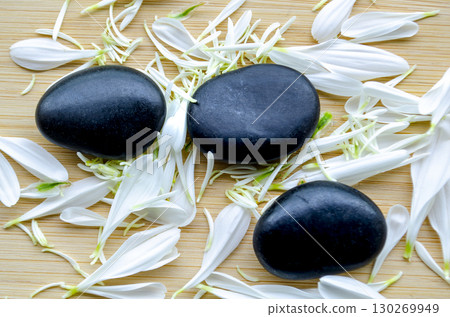 Top view of fresh white flower next to stacked black stones natural balance with customizable space for text 130269949